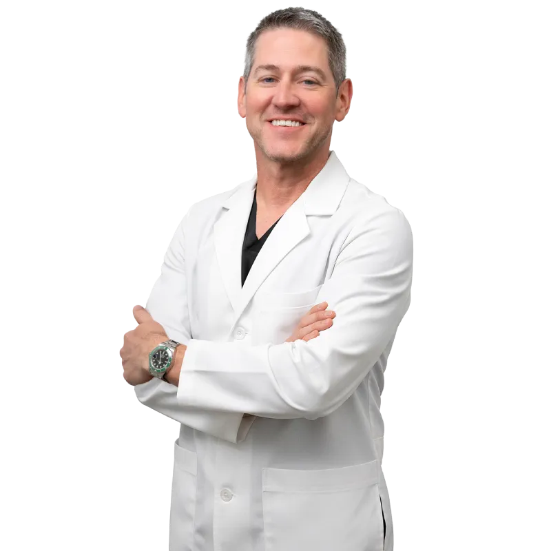 Dr. Shane Volney, board-certified physician at Vein Treatment Clinic, wearing a white coat and smiling confidently