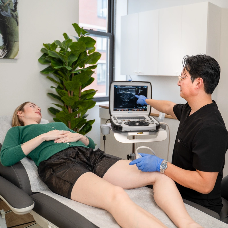 A healthcare provider performs an ultrasound exam on a patient in a clinical setting.
